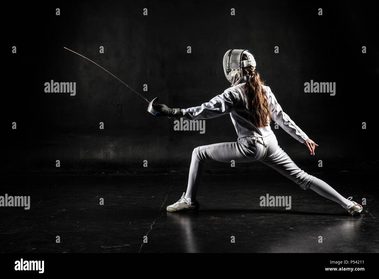 Female fencer wearing white fencing costume isolated on black