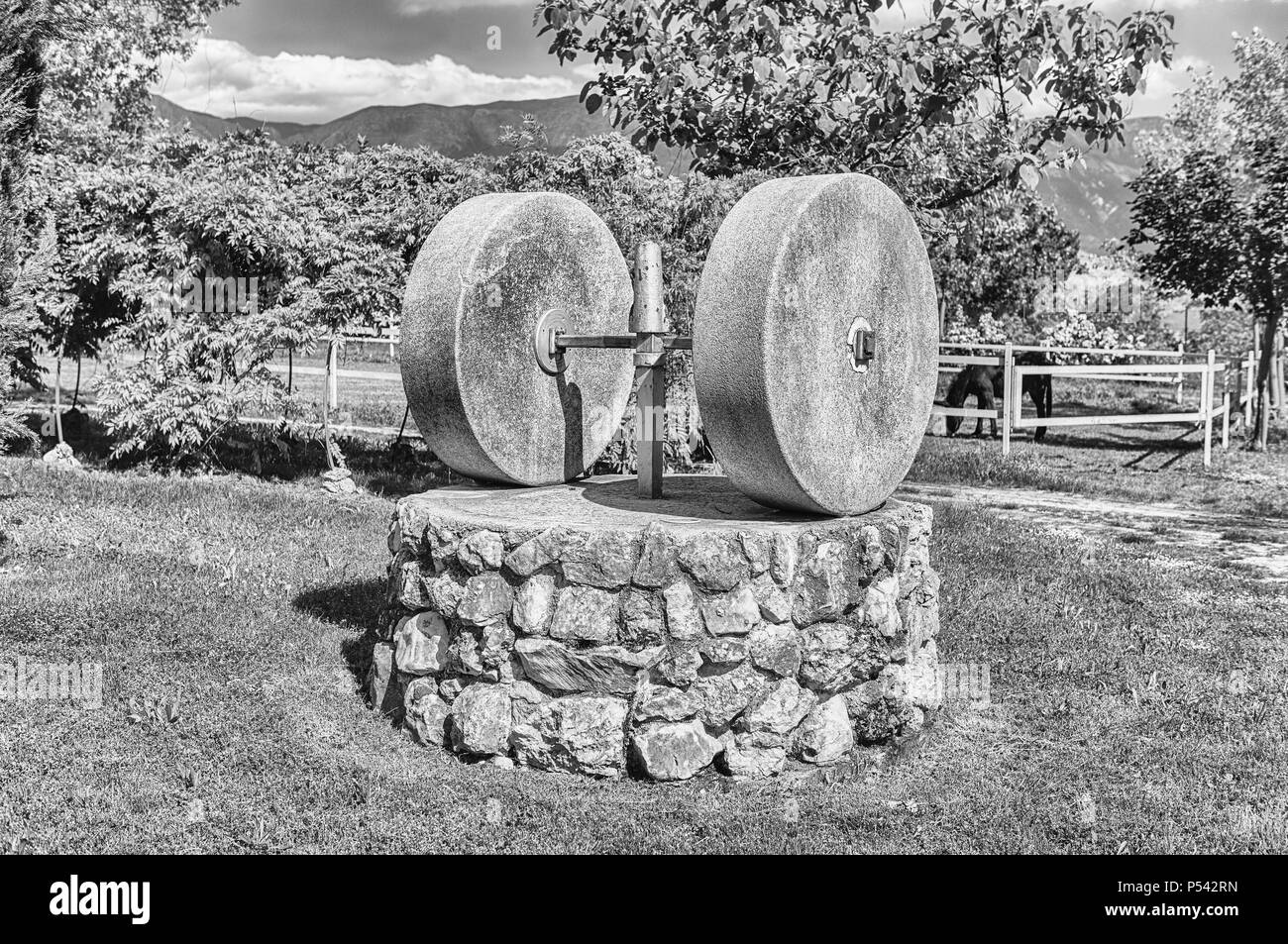 Ancient olive press with two millstones in the countryside Stock Photo