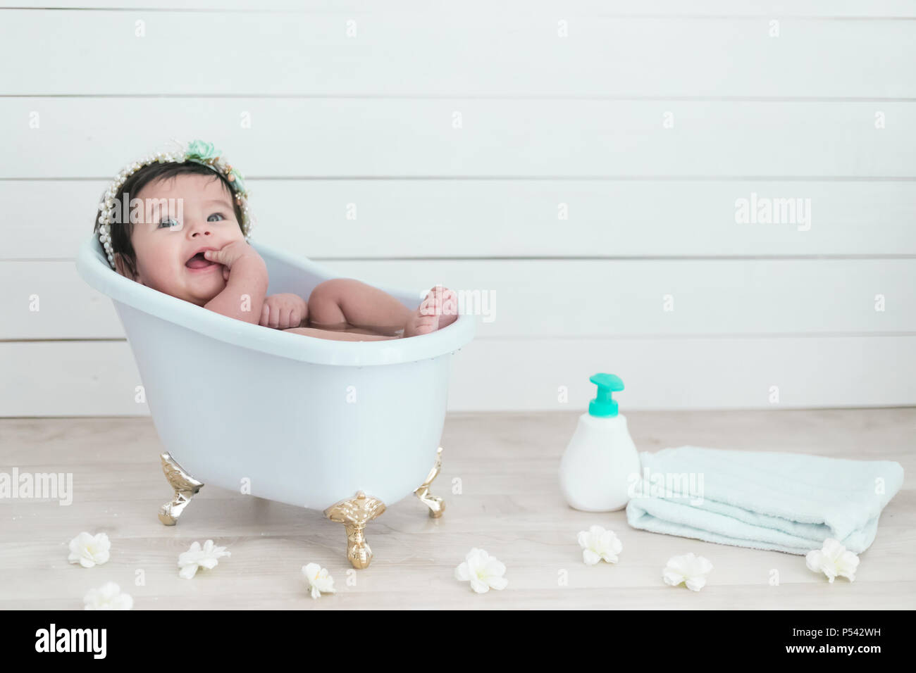 Happy pretty baby taking a shower in a victorian bath tube Stock Photo