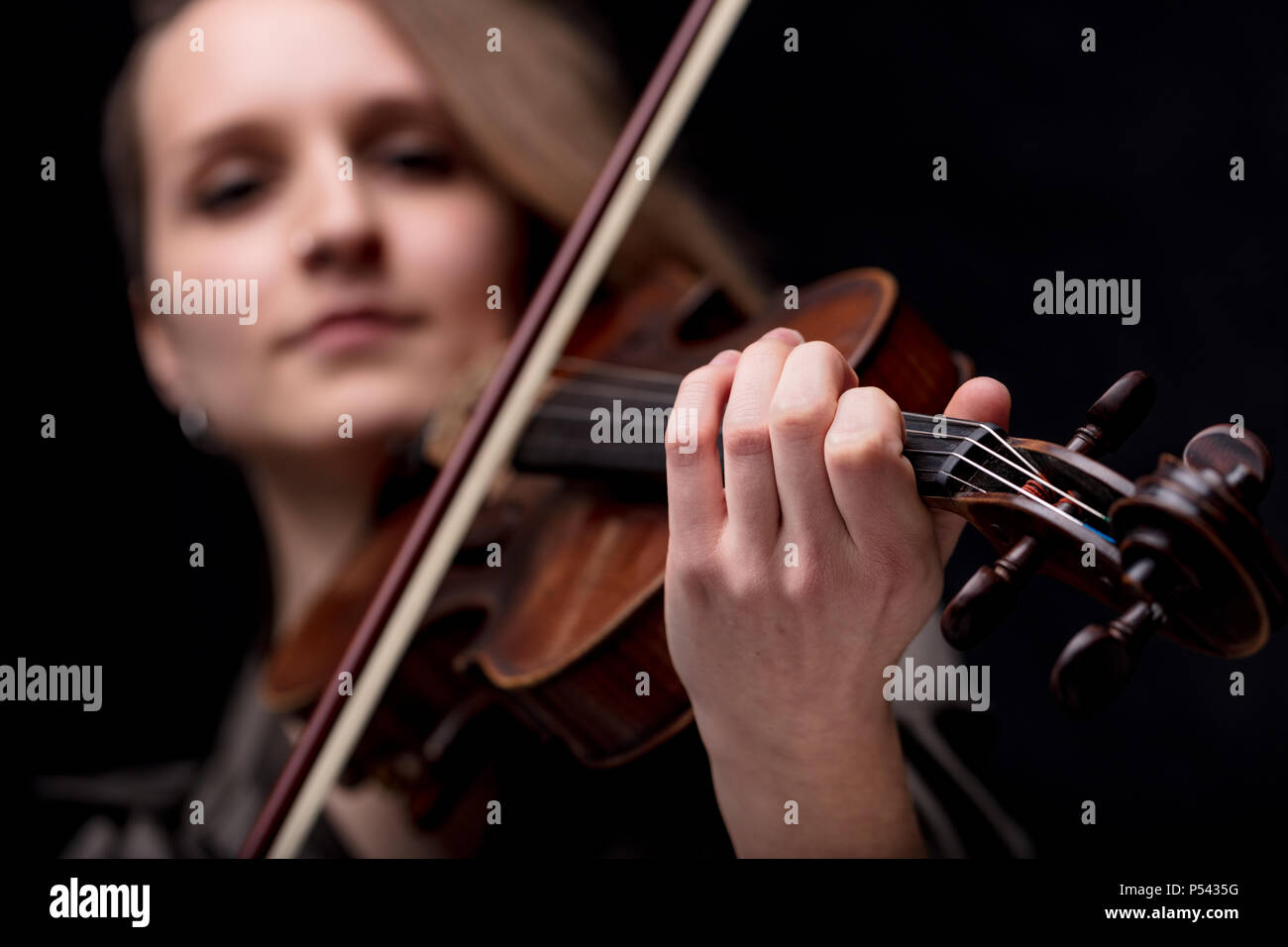 focus on the hand of a baroque violinist player on a black background, she's very serios and determined Stock Photo