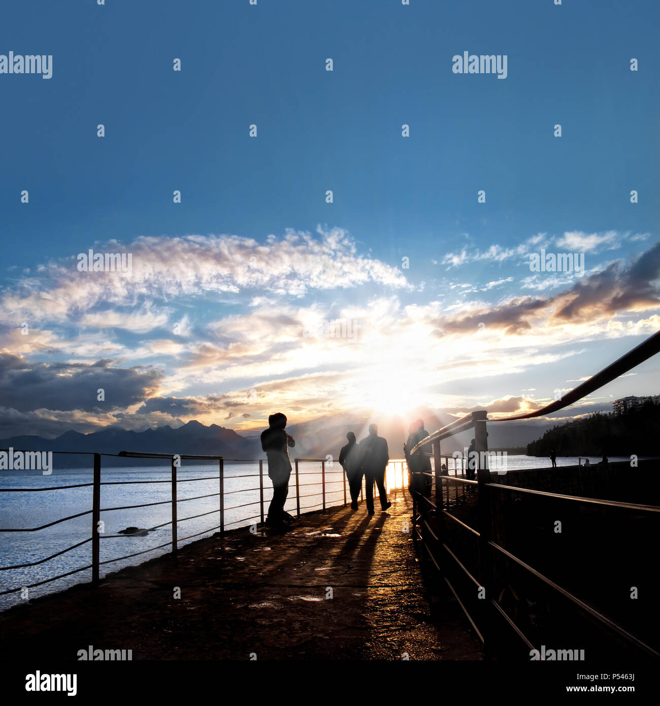 silhouetted people walking on street over sunset sky with sunbeam Stock ...