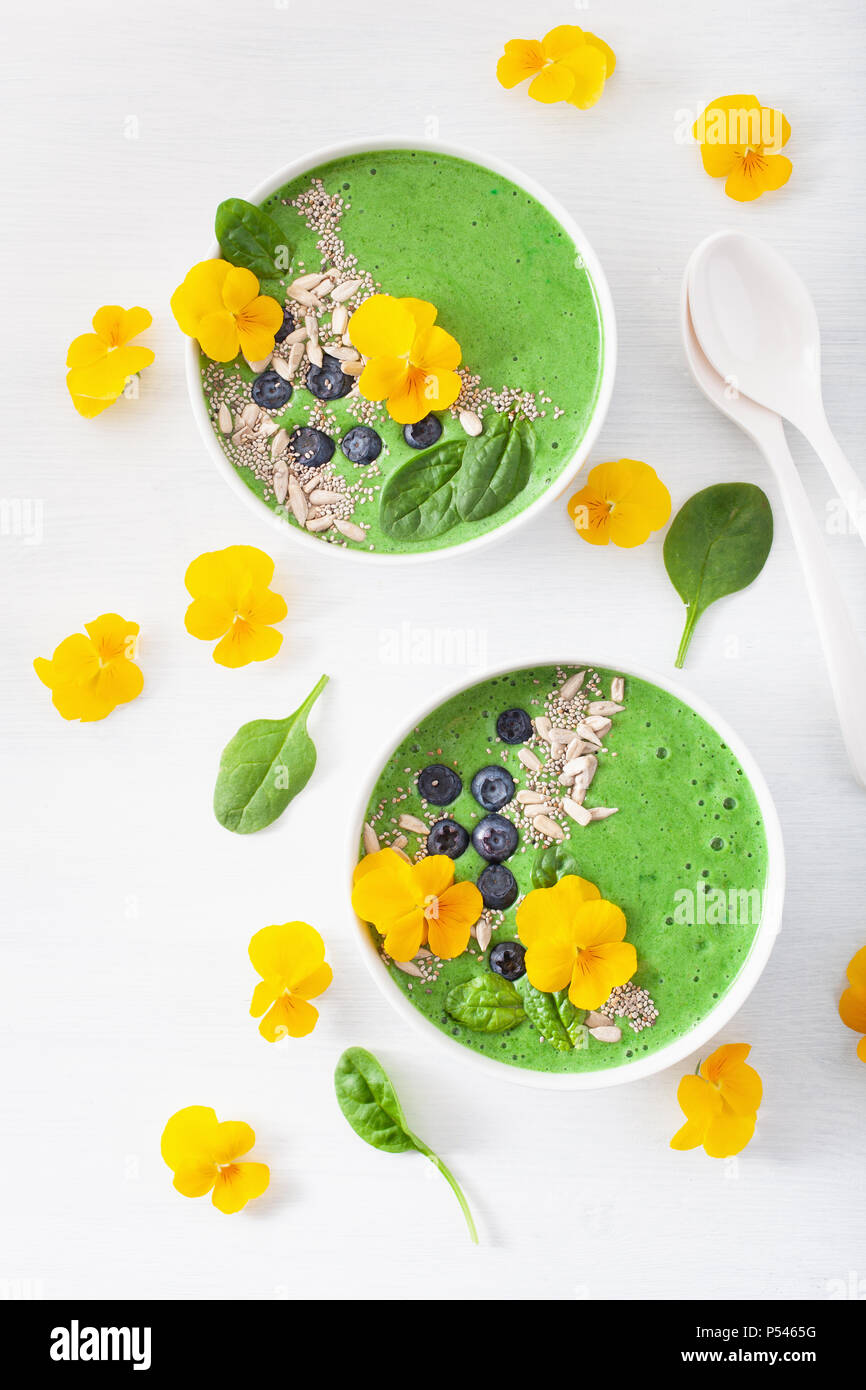 green spinach smoothie bowl with blueberry, chia seed and edible pansy