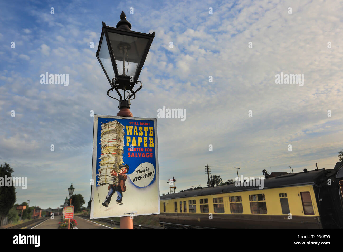 1940's community spirit WWII wartime poster on lamp post of vintage gas lantern, empty heritage railway station, UK: Waste Paper wanted for Salvage. Stock Photo