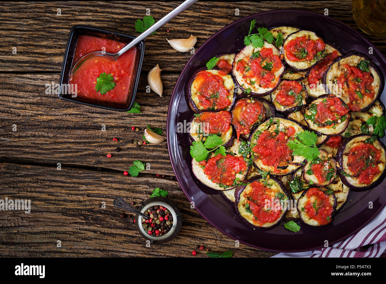 Eggplant grilled with tomato sauce, garlic, cilantro and mint. Vegan food. Grilled aubergine