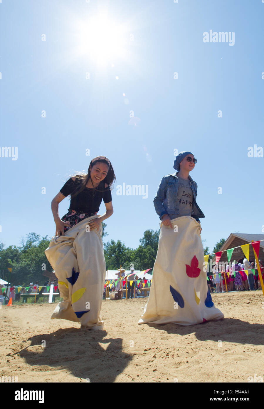 KAZAN, RUSSIA - JUNE 23, 2018: Traditional Tatar festival Sabantuy - Young women having fun playing traditional game, jumps in bags under the sun Stock Photo