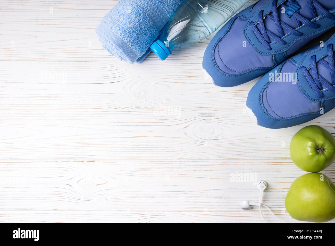 Flat lay sport shoes, bottle of water, apples, towel and earphones on white background. Sport equipment. Healthy lifestyle, sport and diet concept. Co Stock Photo