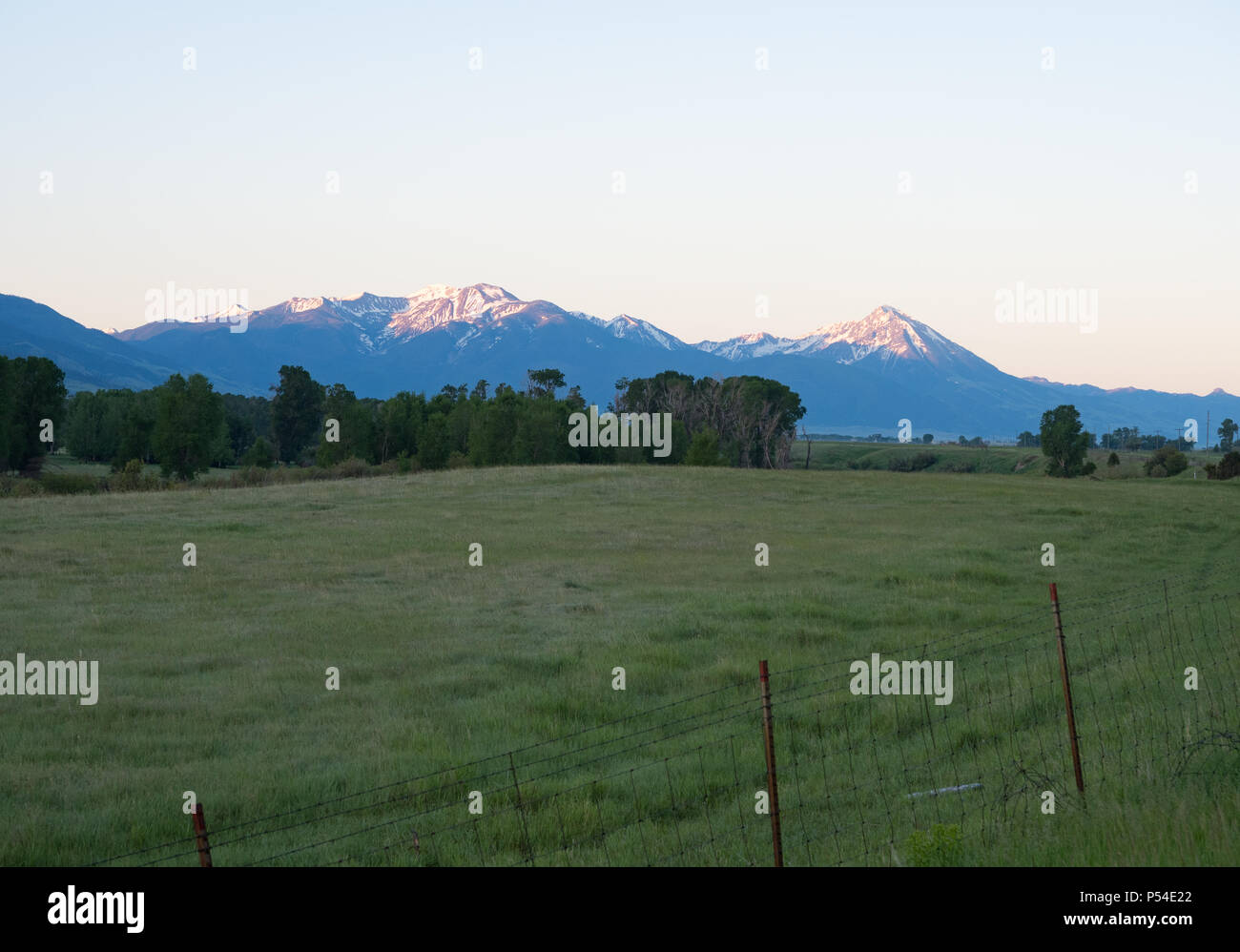 Snow capped mountains in the Absaroka Range in Montana with a fenced pasture in the foreground. Photographed at sunrise. Stock Photo