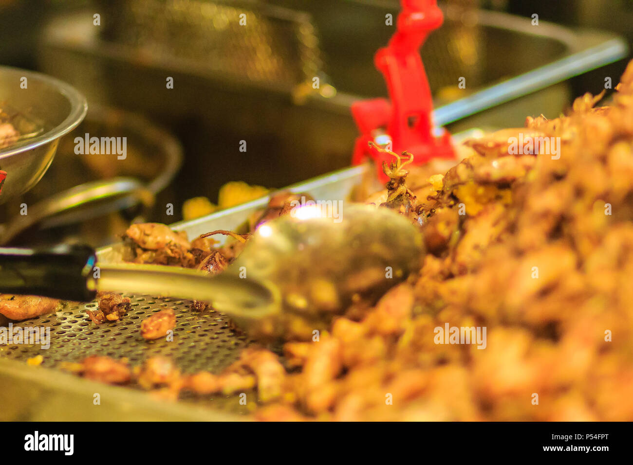 Vendor is selling fried baby squid with garlic in night market at Bangkok, Thailand. Stock Photo