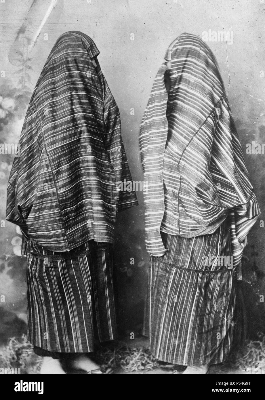 Scutari, Albania. Women in ordinary street costume of red and white cloth. The seams are joined with minute crochet and worked in red or color combinations. Under the skirt cloth which is tied like an apron around the waist are worn voluminous trousers on the Turkish style of black shiny cloth. August 1921 Stock Photo