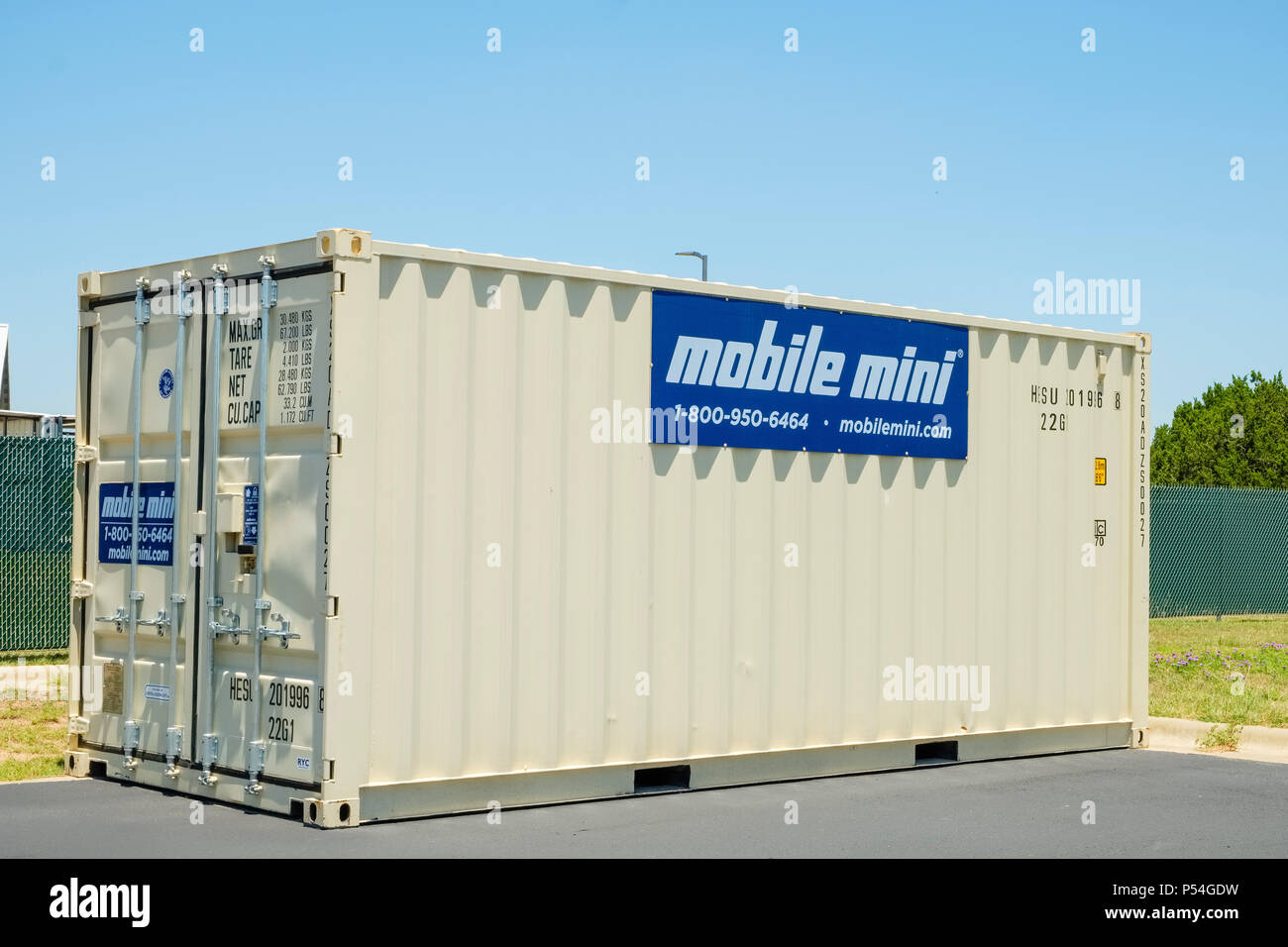 Steel mobile storage shipping container setting outside behind local small business Stock Photo