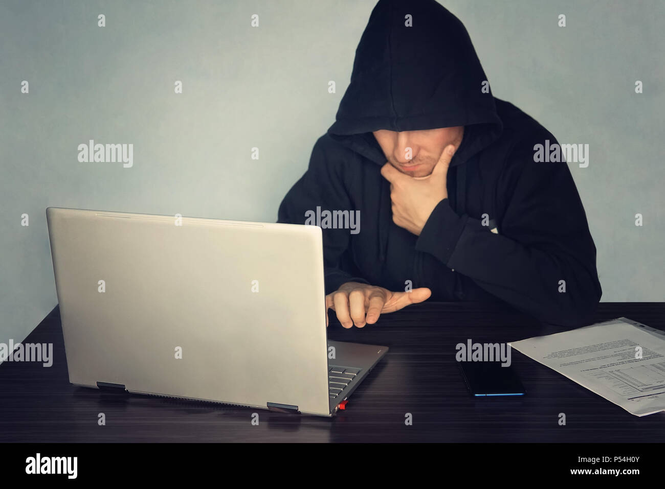 Anonymous hacker programmer uses a laptop to hack the system. Stealing personal data. Creation and infection of malicious virus. The concept of cyber  Stock Photo
