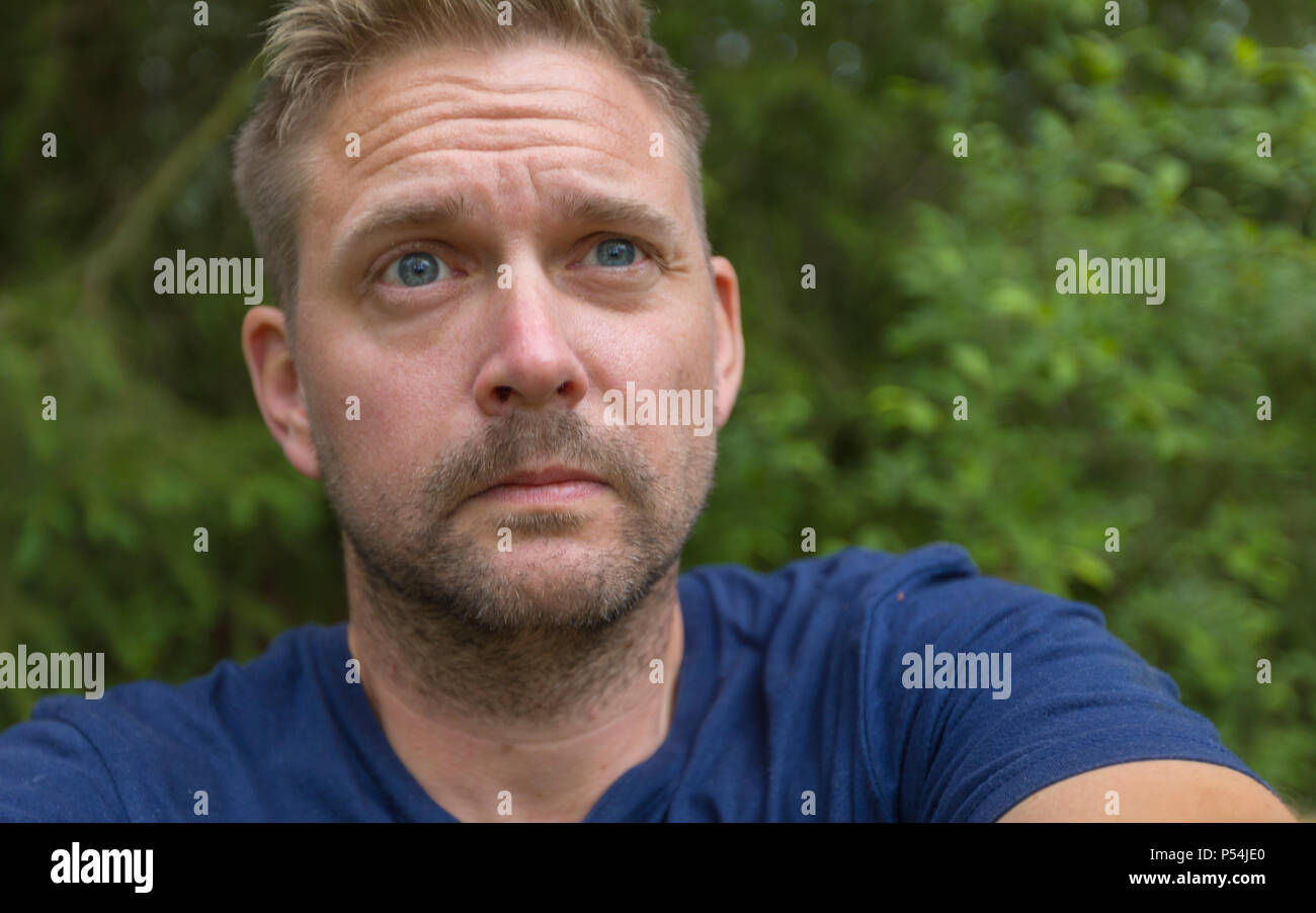 Adult caucasian man looking up and concerned or in despair Stock Photo