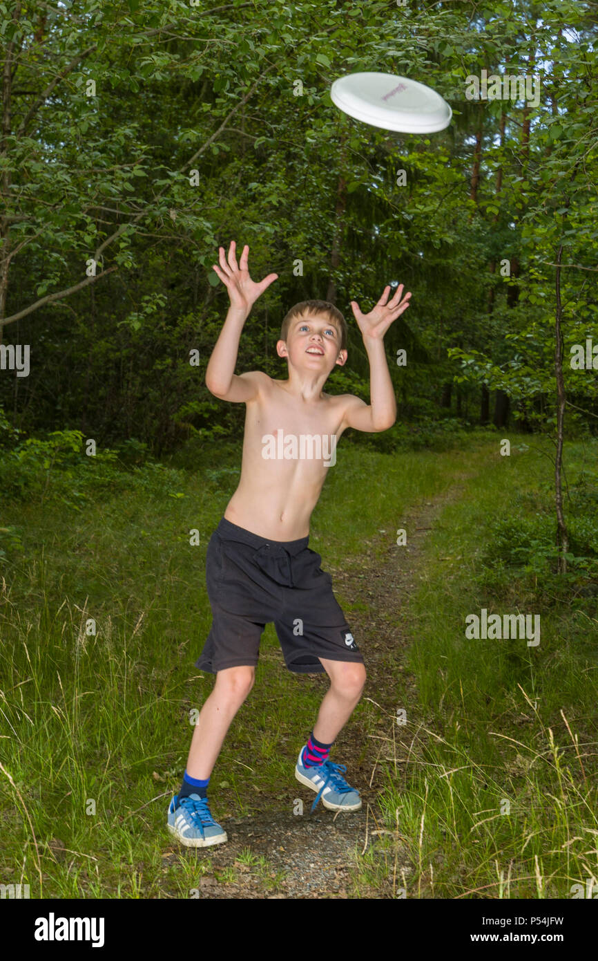 Shirtless caucasian young boy having fun throwing and catching a frisbee outdoors Stock Photo