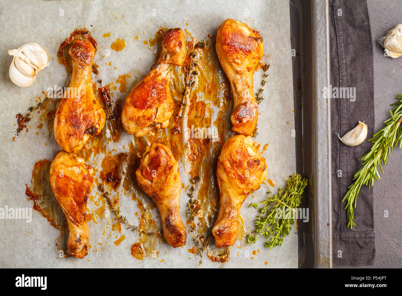 Grilled spicy chicken legs baked with garlic, rosemary and thyme on the pan. Top view Stock Photo