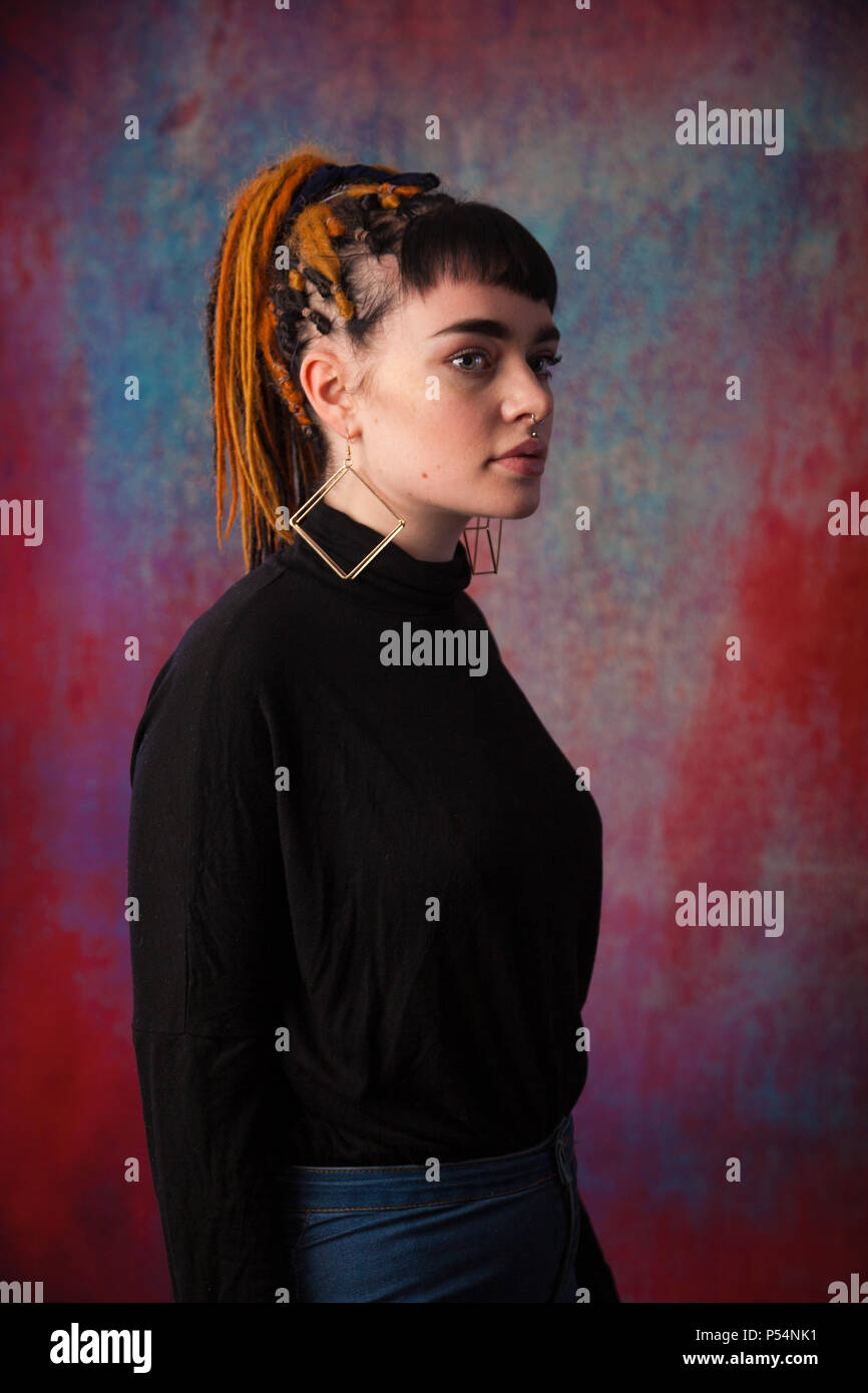 An alternative looking girl standing in a studio wearing a band