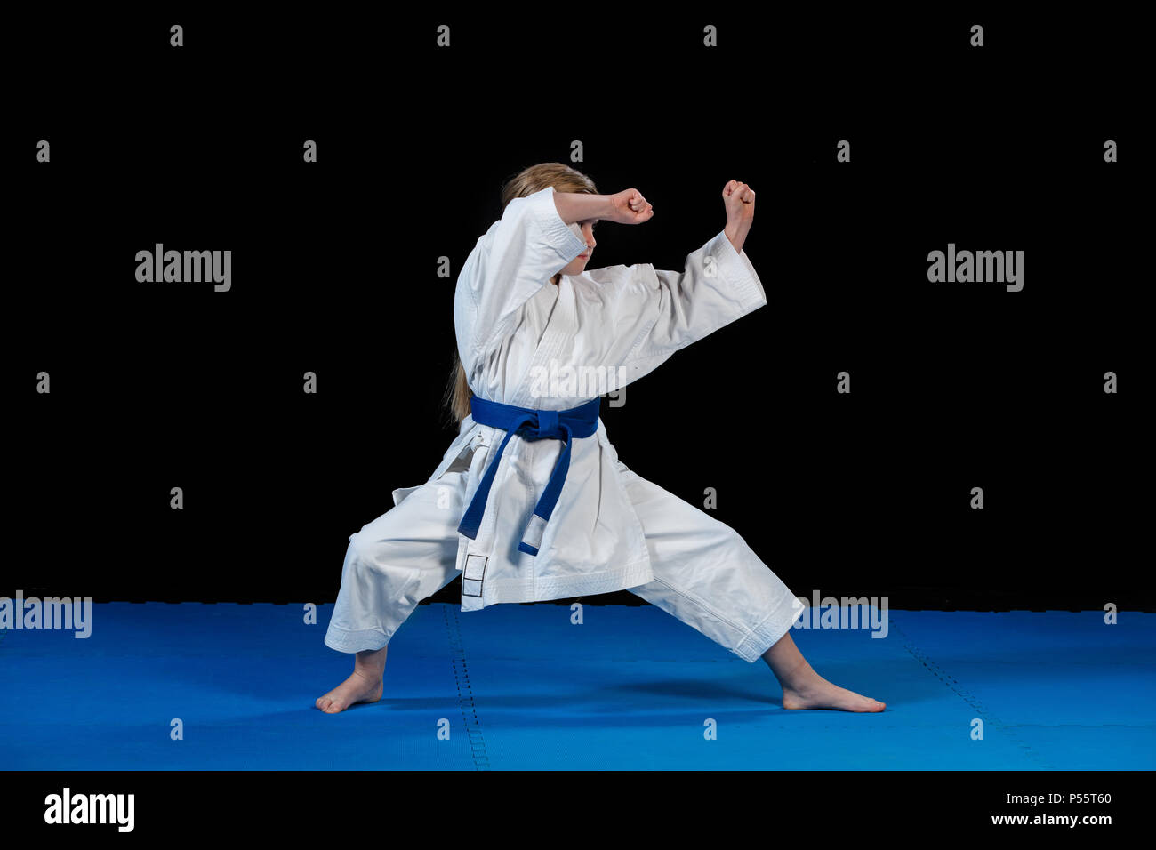 sweet little girl in martial arts practice like karate kid alone isolated on black background Stock Photo