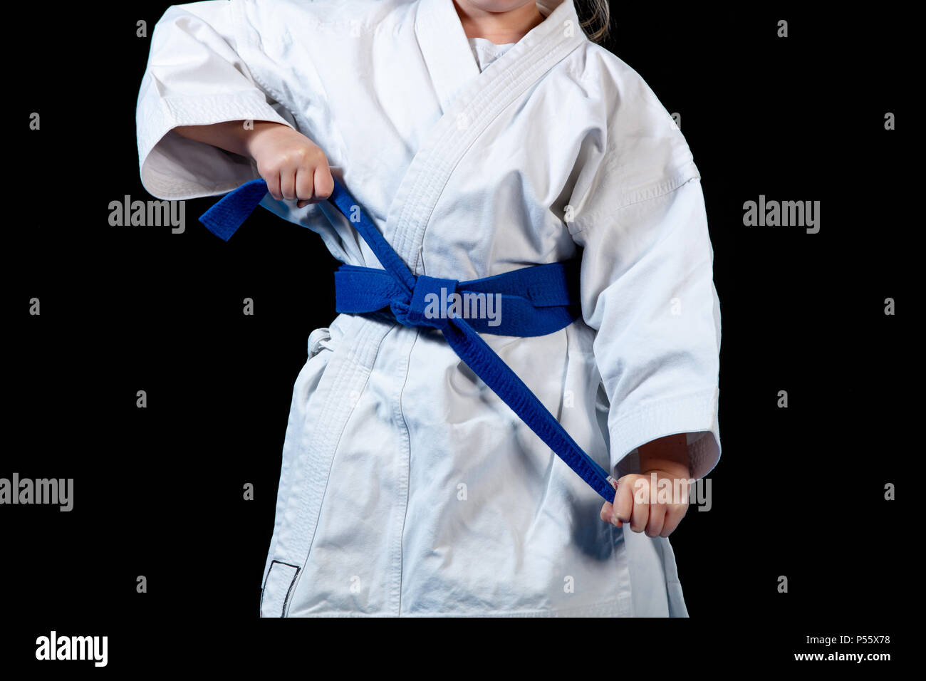 sweet little girl in martial arts practice like karate kid alone isolated on black background