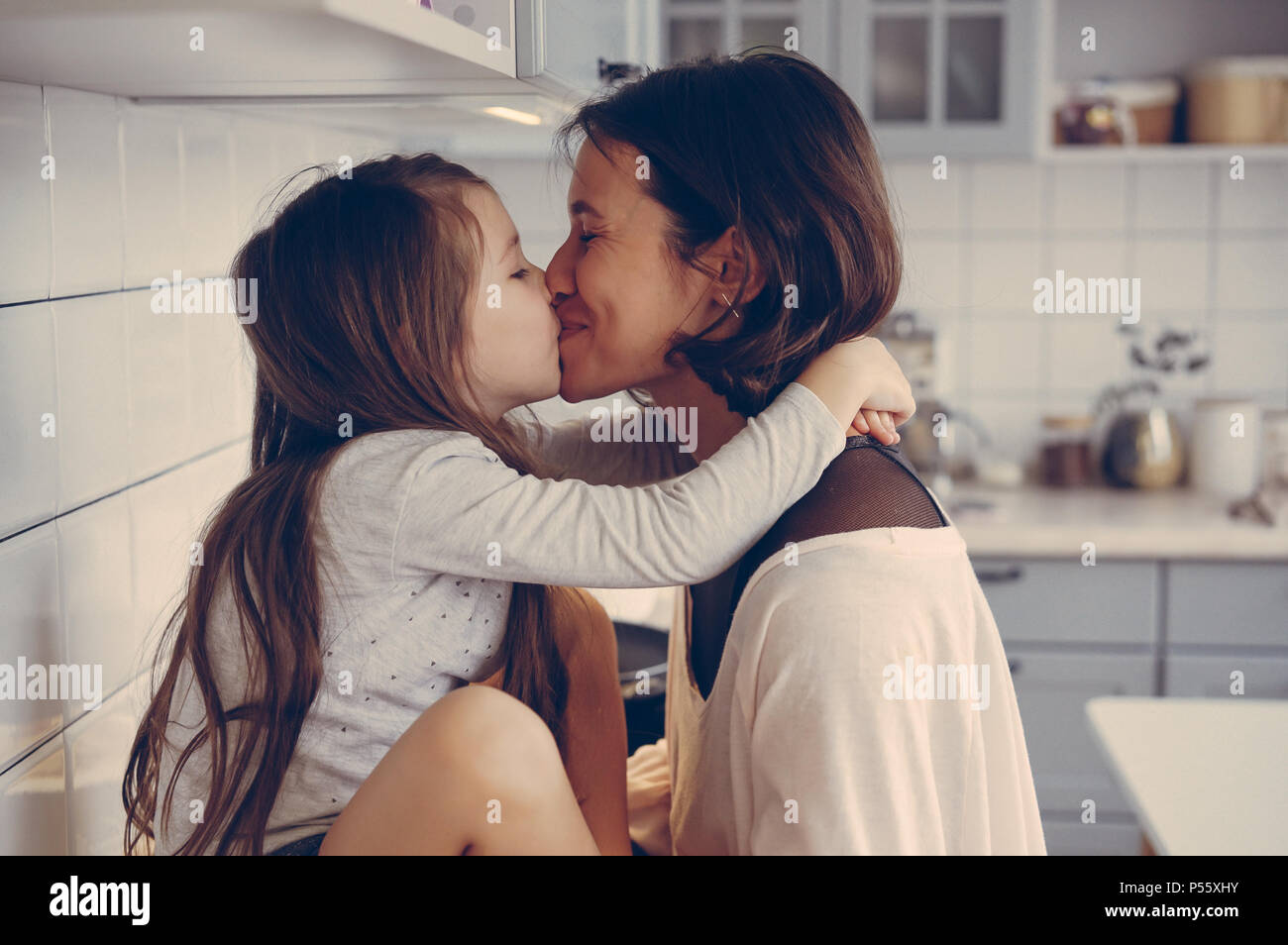 Мама и дочка целуются. Мама целует дочь. Мама с дочкой поцелуй. Мама целуется с дочкой. Мама целует на кухне.