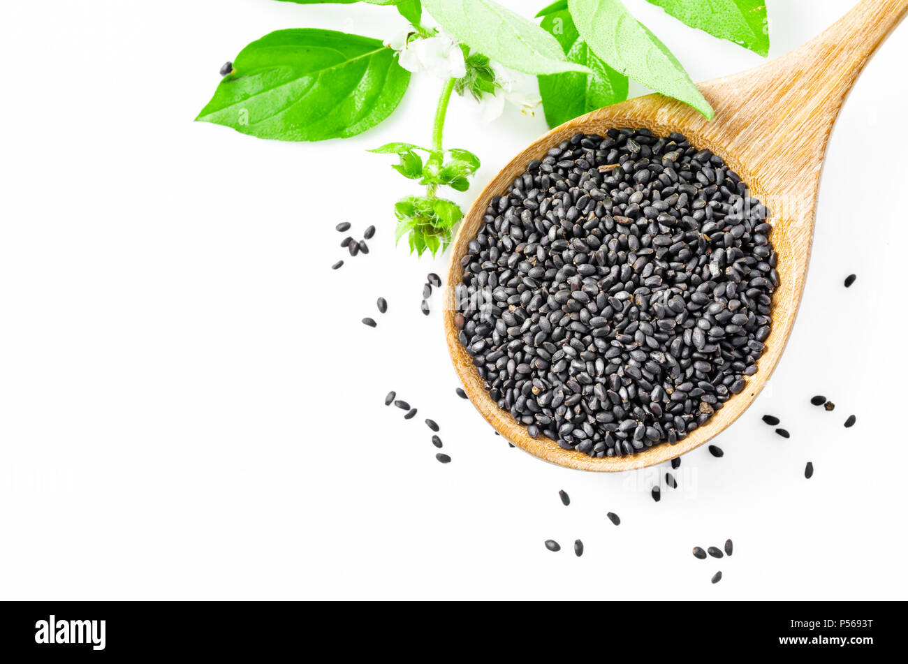 Hoary basil seeds in wooden spoon with green leaf isolated on white