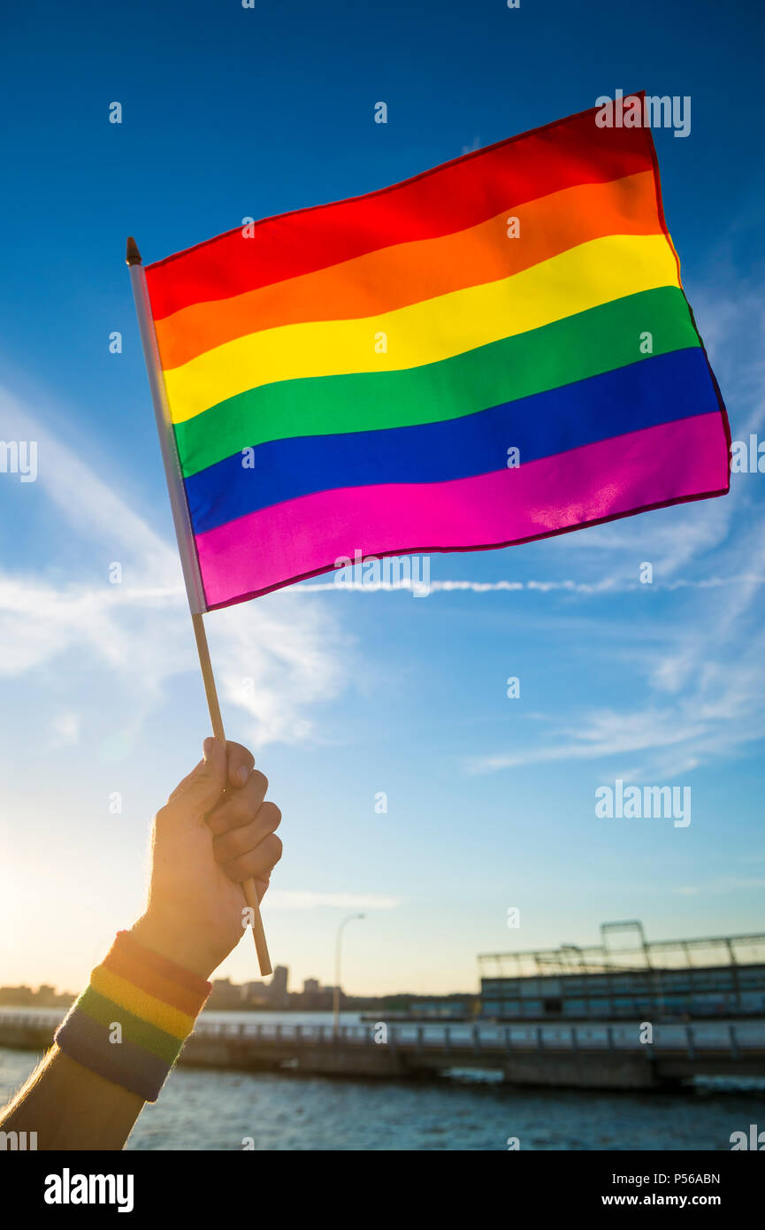 Colorful rainbow gay pride flag being waved in the breeze by a hand ...