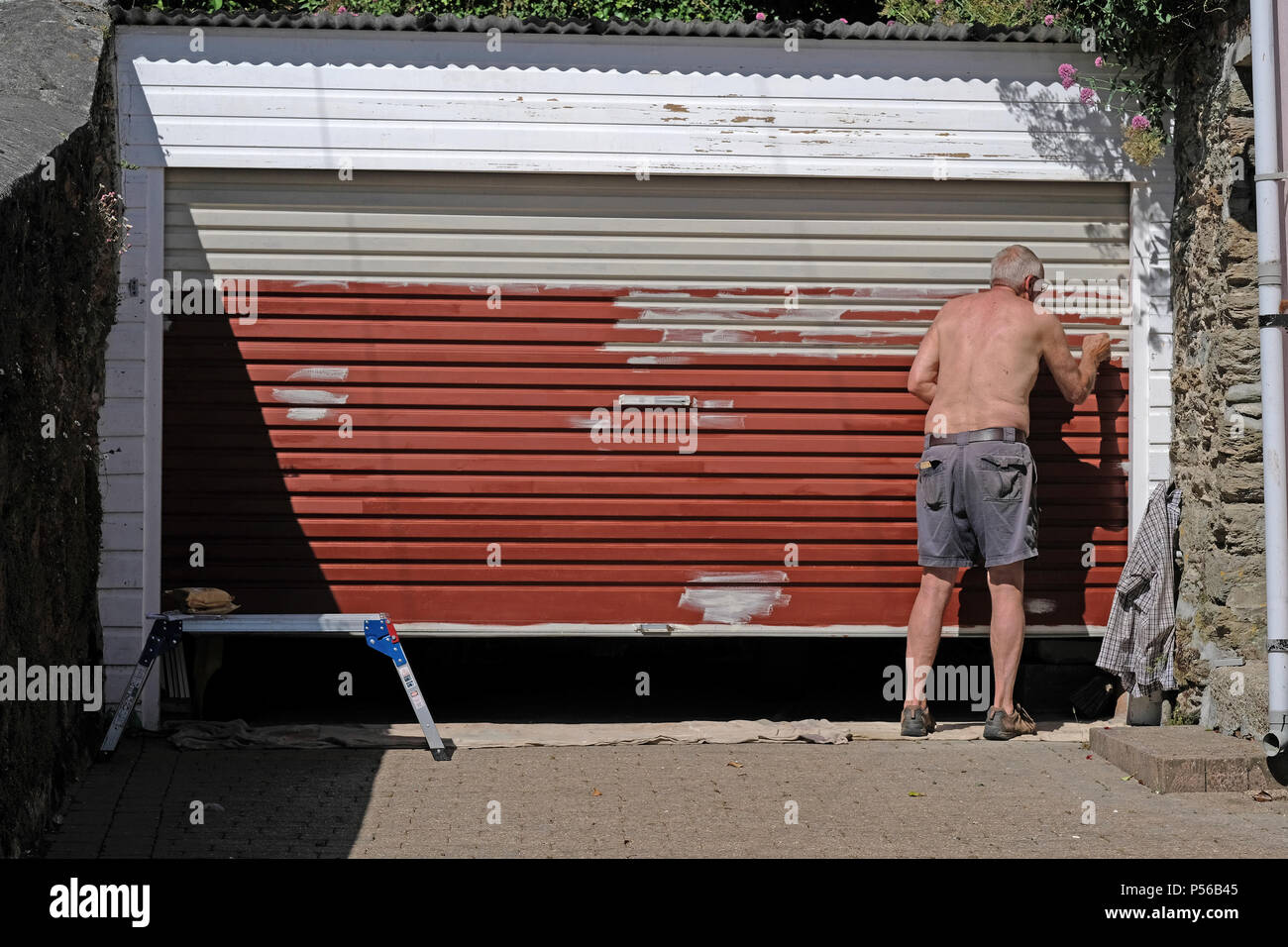 An old man painting a garage door Stock Photo