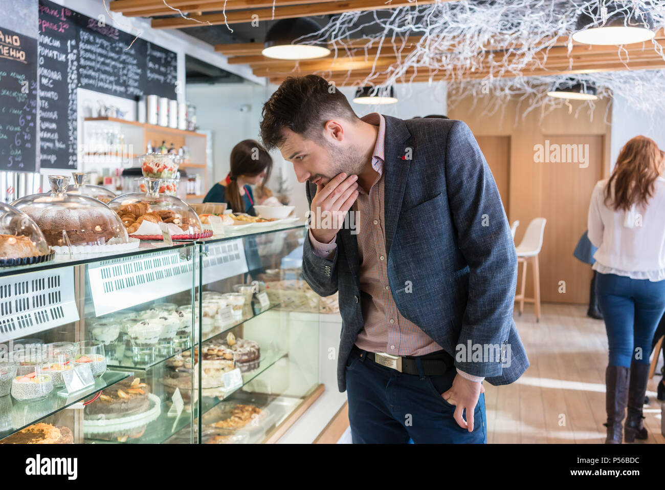 Undecided man looking at various cakes exposed in the showcase Stock Photo