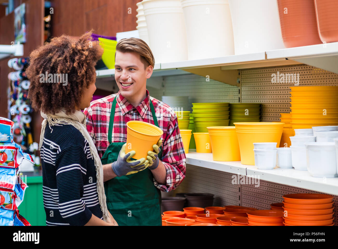 Customer buying plastic pots at the advice of a helpful worker in flower shop Stock Photo