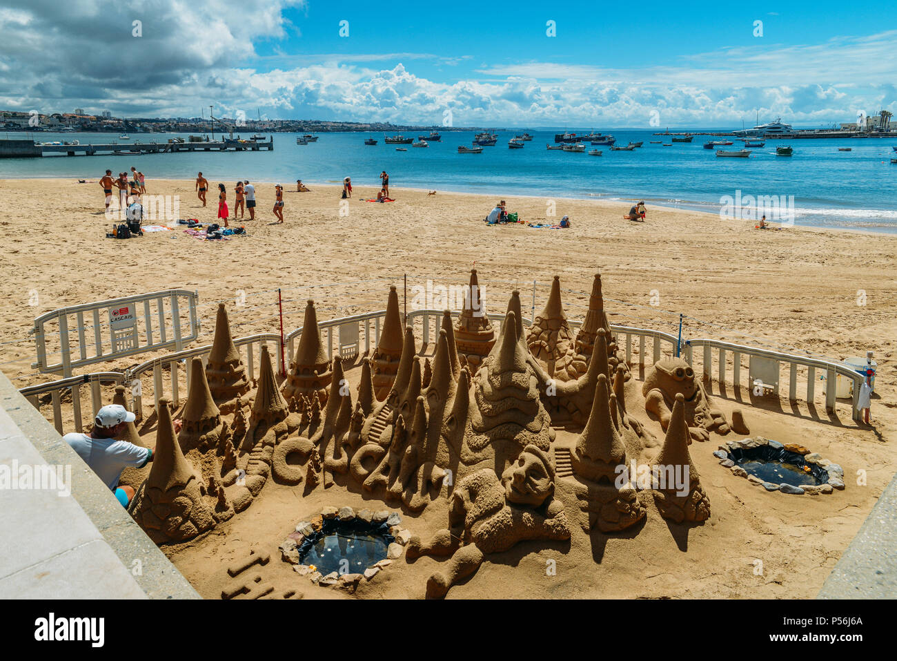Cascais, Portugal - June 9, 2018: Man builds a sand castle on Praia da Ribeira beach in Cascais, Portugal Stock Photo