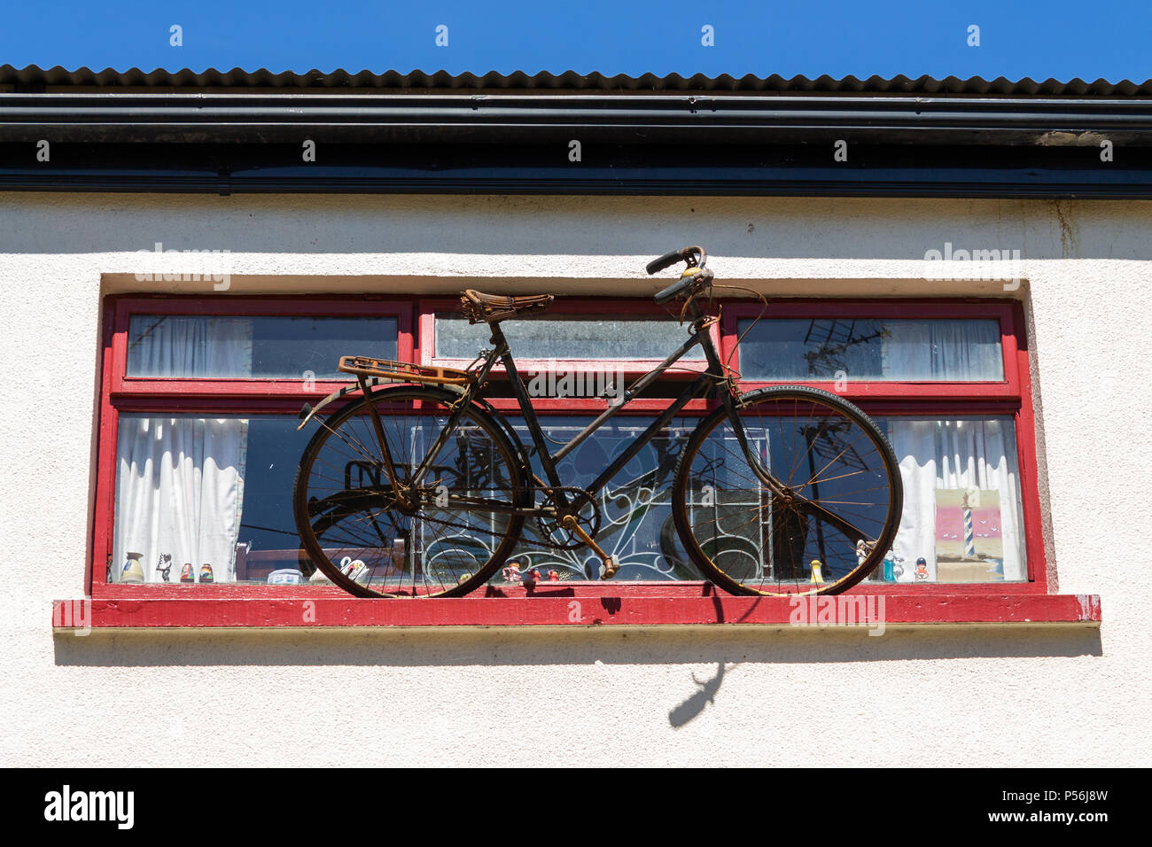 bicycle or bike balanced on a window ledge acting as a sign for the shop below. Stock Photo
