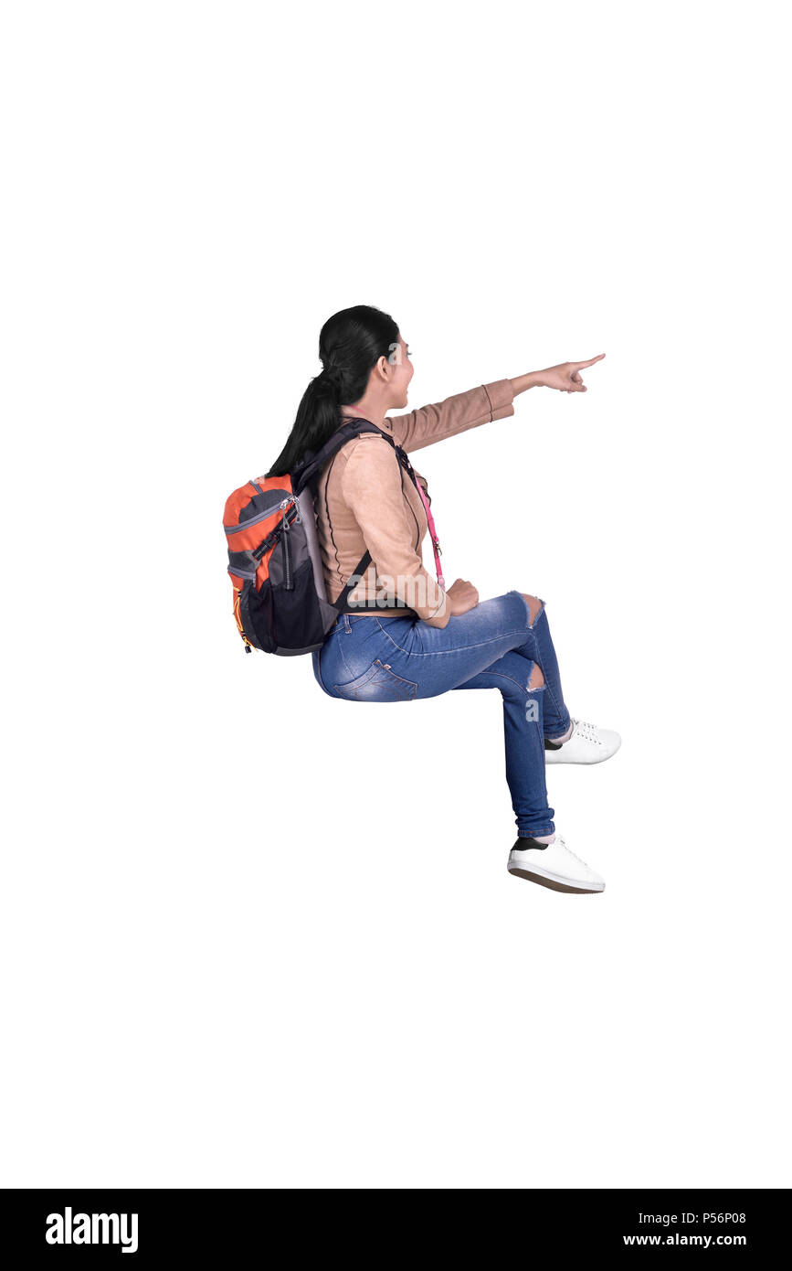 Portrait of asian traveler woman sitting and pointing to something posing isolated over white background Stock Photo