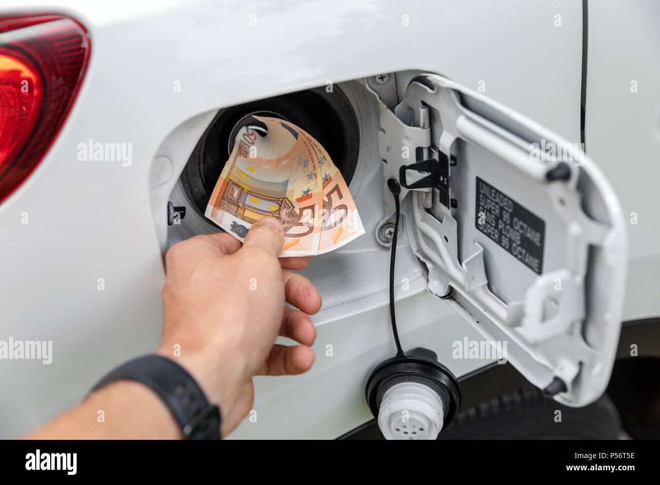 transport costs - hand inserting money in car fuel tank Stock Photo
