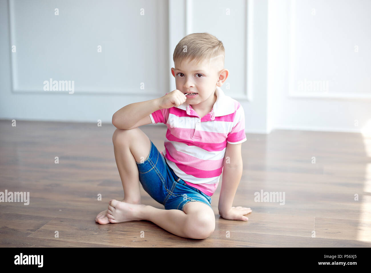 Little Cute Boy With Modern Haircut Sitting On The Floor In Big