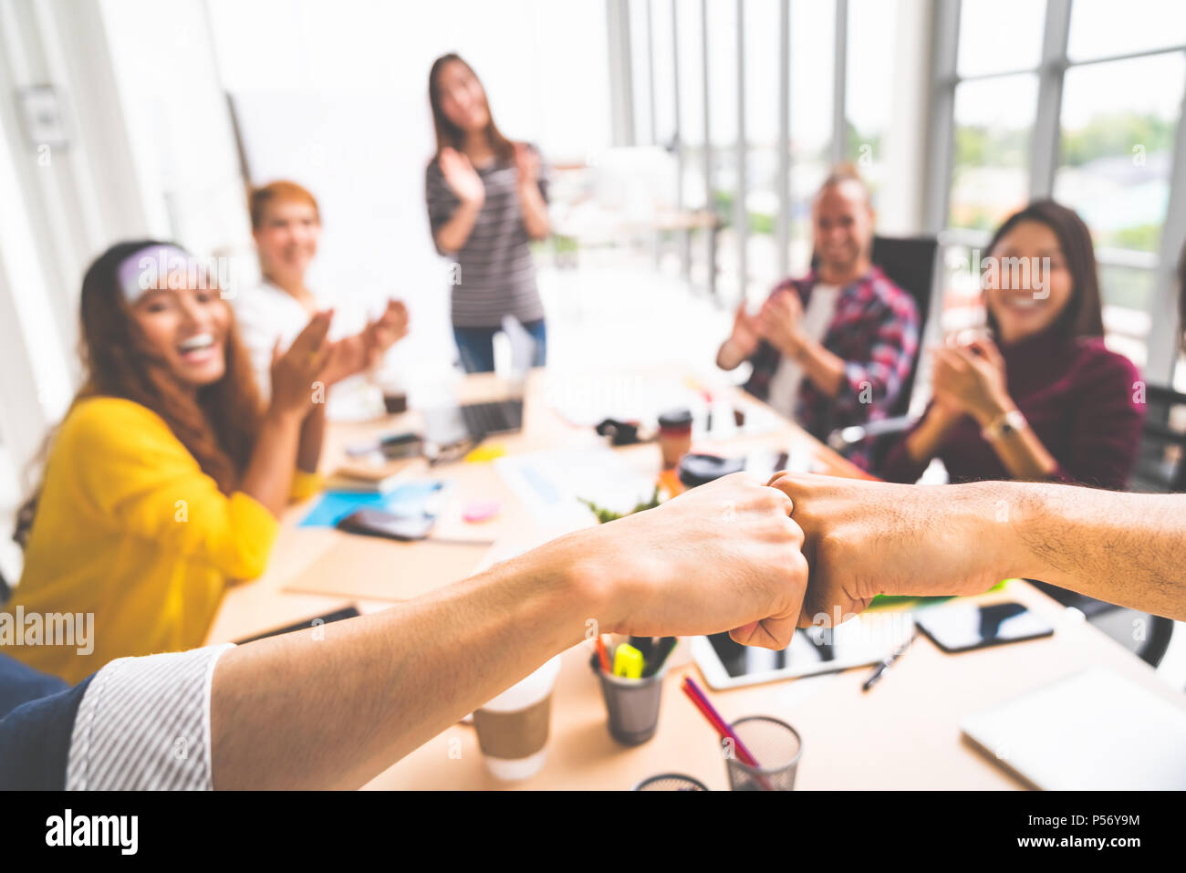 Business partners or men coworkers fist bump in team meeting, multiethnic diverse group of happy colleagues clapping hands. Teamwork concept Stock Photo