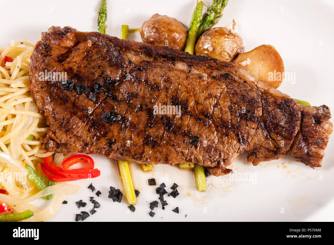 Grilled beef steaks with asparagus and pasta, black rock salt Stock