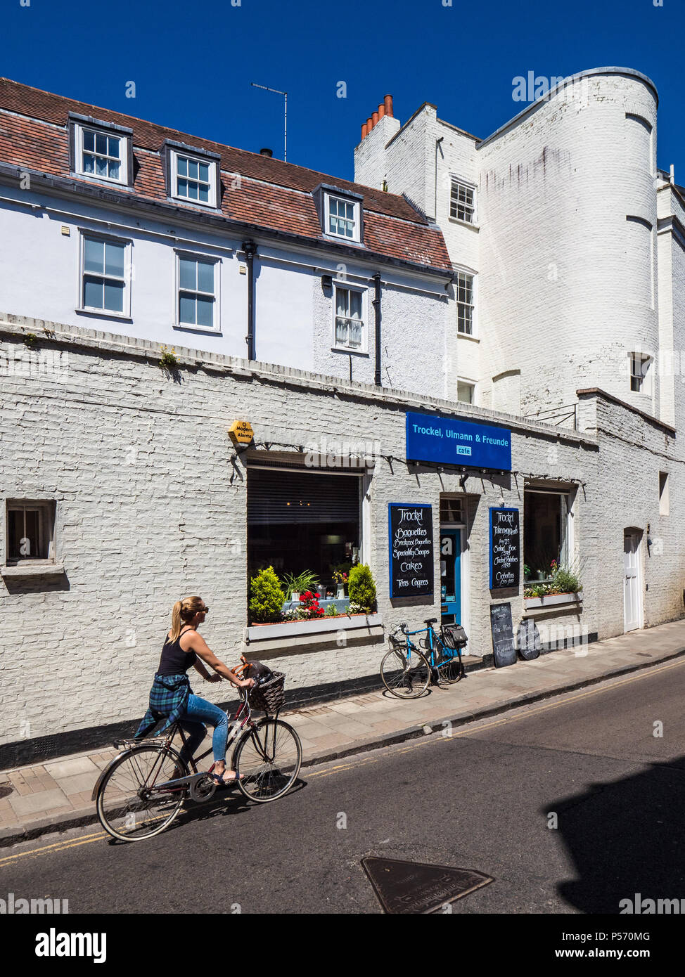Trockel, Ulmann & Freunde Cafe in Cambridge - cyclist rides past the German style cafe on Pembroke Street central Cambridge Stock Photo