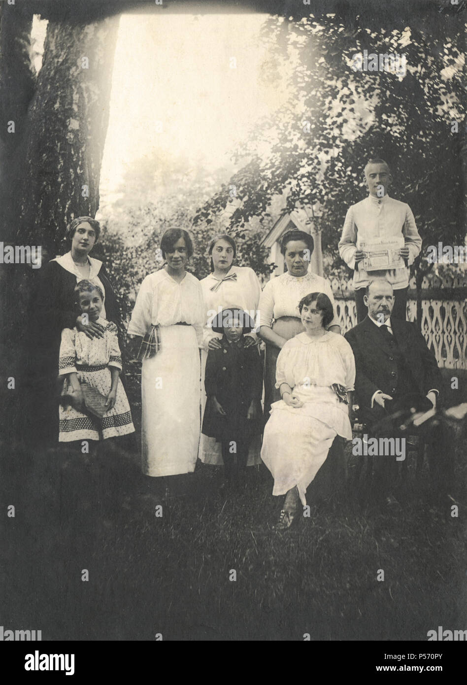 Vintage photo of the prosperous and happy family in the garden  in Russia, 1914. The newspaper 'Trudovaya kopeika'  ('The Worker's Penny') in the hands of young man Stock Photo