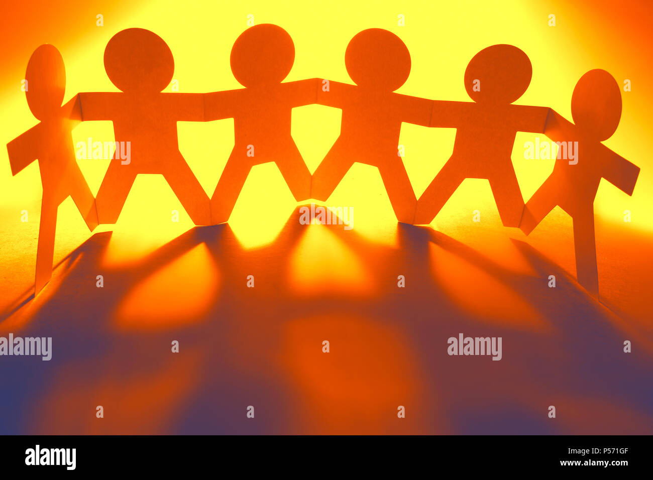Team of paper chain people in a row holding hands Stock Photo Alamy