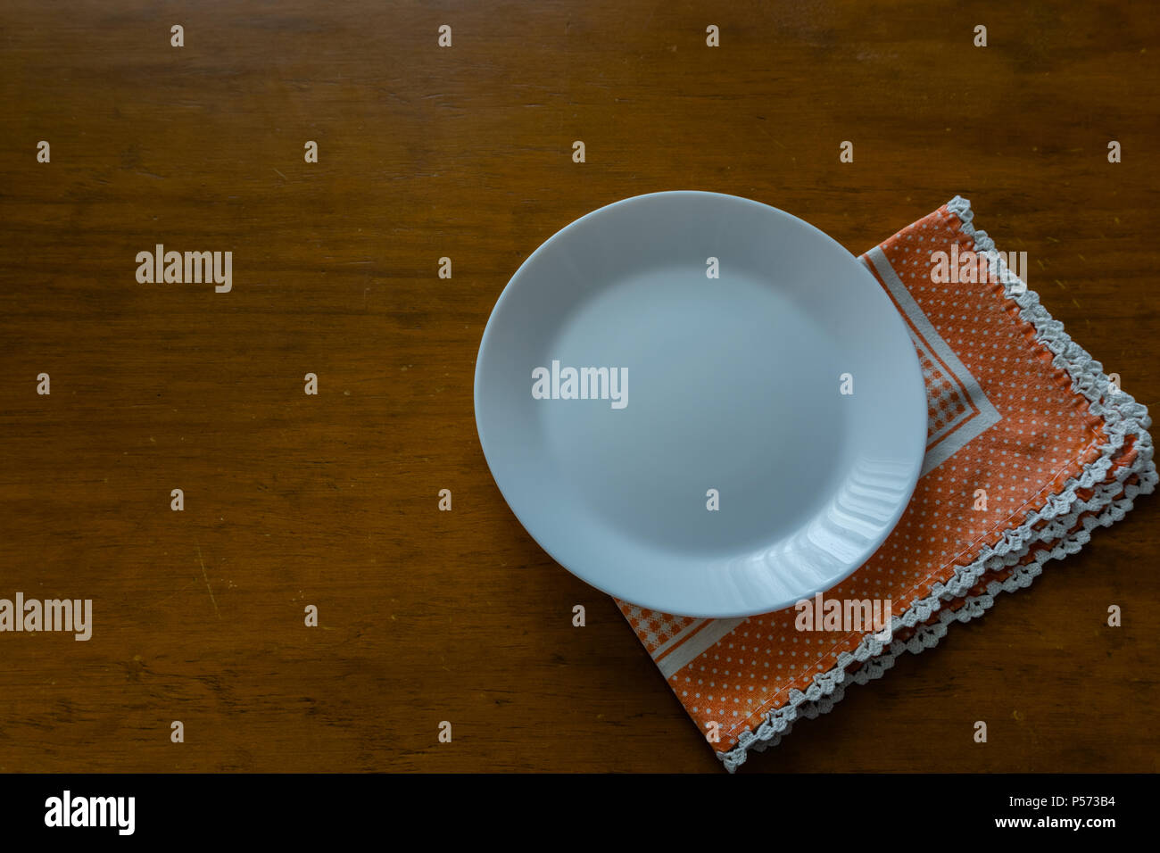 Empty plate on wooden tabletop with tablecloth. Stock Photo