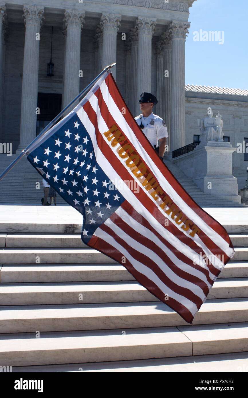 Washington, DC, USA. 25th June, 2018. A man stood outside the Supreme Court building with an upside-down American flag on a pole, with the words, ''In God We Trust'' on it in yellow/gold letters. The Supreme Court building and an officer can be seen in the background. Credit: Evan Golub/ZUMA Wire/Alamy Live News Stock Photo