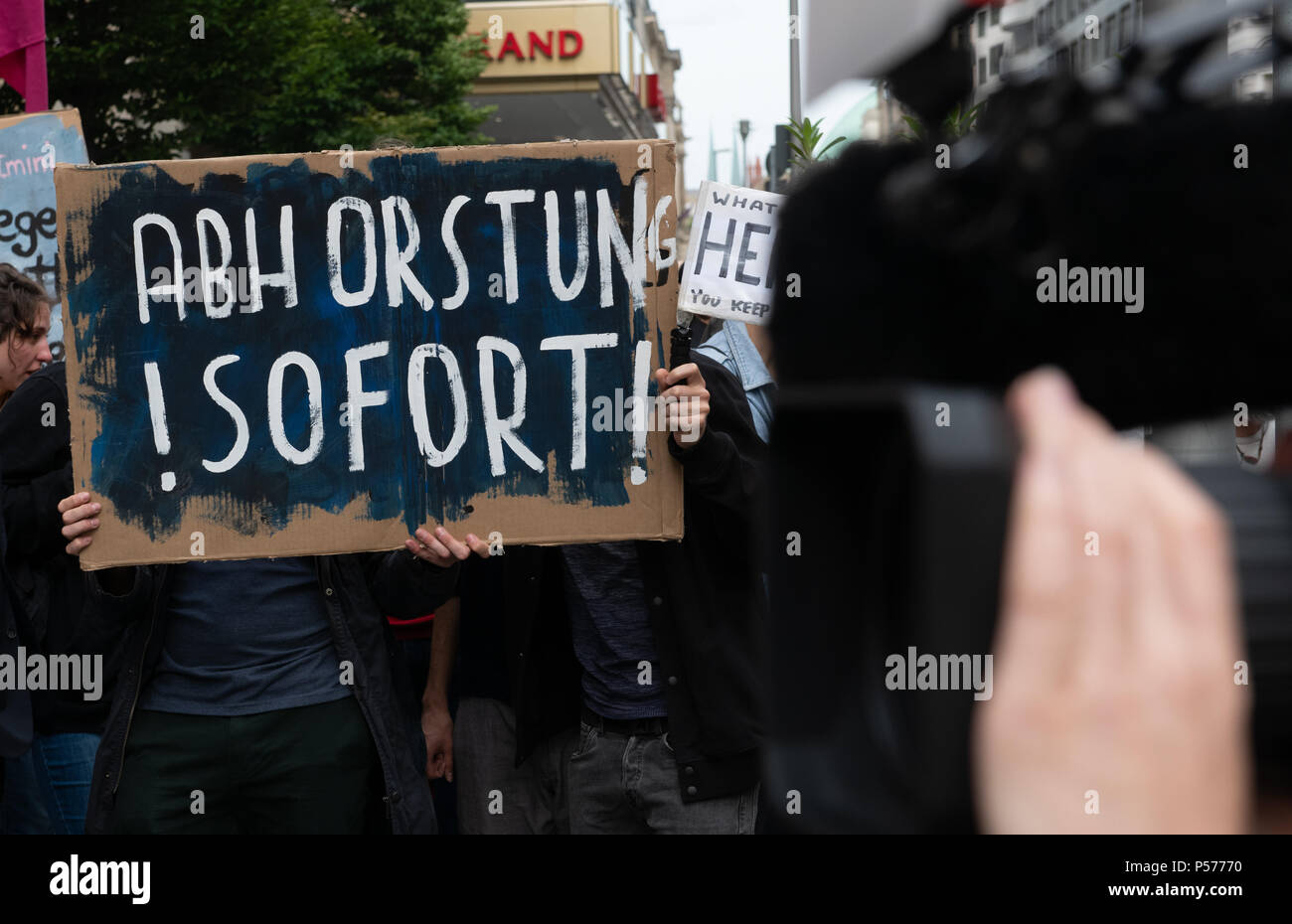 Berlin, Germany. 25th June, 2018. A protestor carrying a sign that reads 'Abhorstung! Sofort' (lit. dehorstation! now; play on words) stands outside the Bavarian state representation. More than 200 people protest against the planned refugee policy of Seehofer of the Christian Social Union (CSU), German Minister of the Interior, Homeland and Building. Credit: Paul Zinken/dpa/Alamy Live News Stock Photo