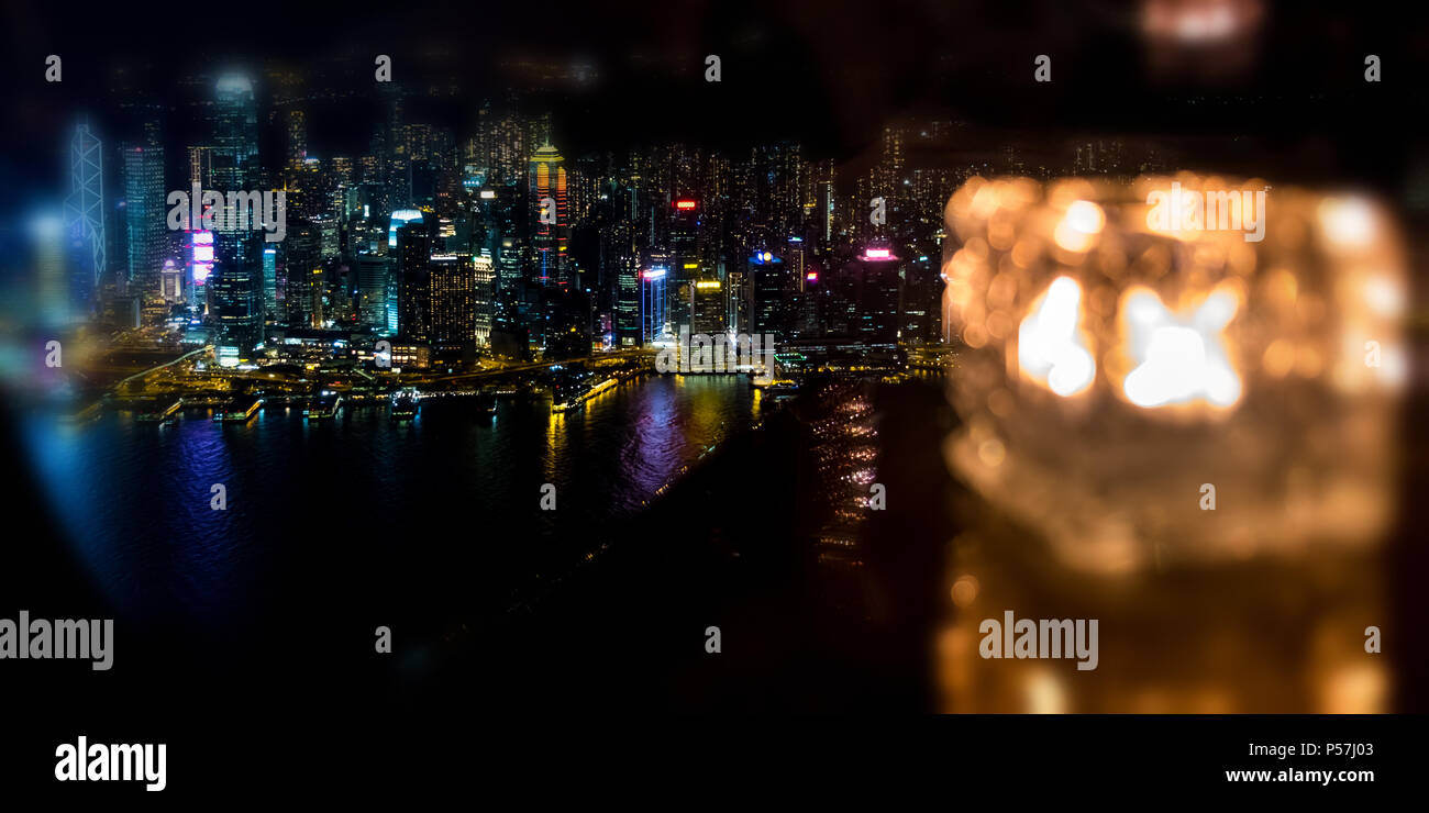 Blurred burning candle in glass cup with Hong Kong island night view