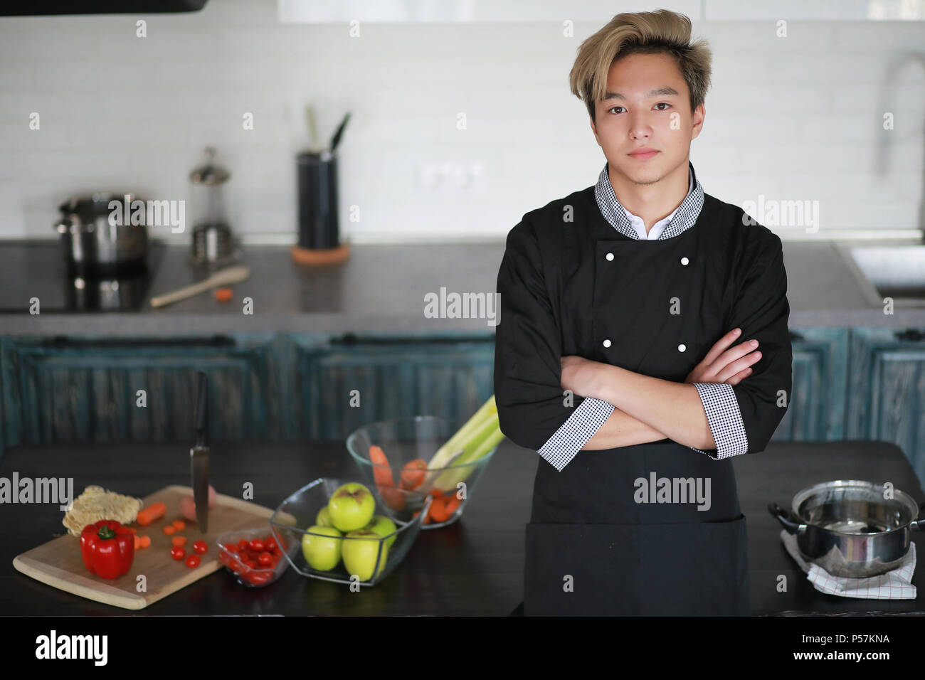 A young Asian cook in the kitchen prepares food in a cook suit Stock ...