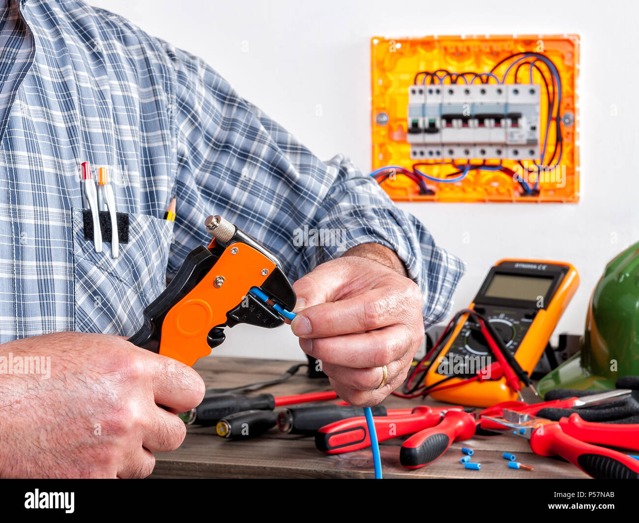 Electrician technician at work with wire stripper on cables in a