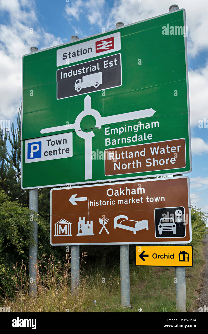 Large new green roundabout road primary route direction sign and brown tourist information sign, Oakham, Rutland, England, UK Stock Photo