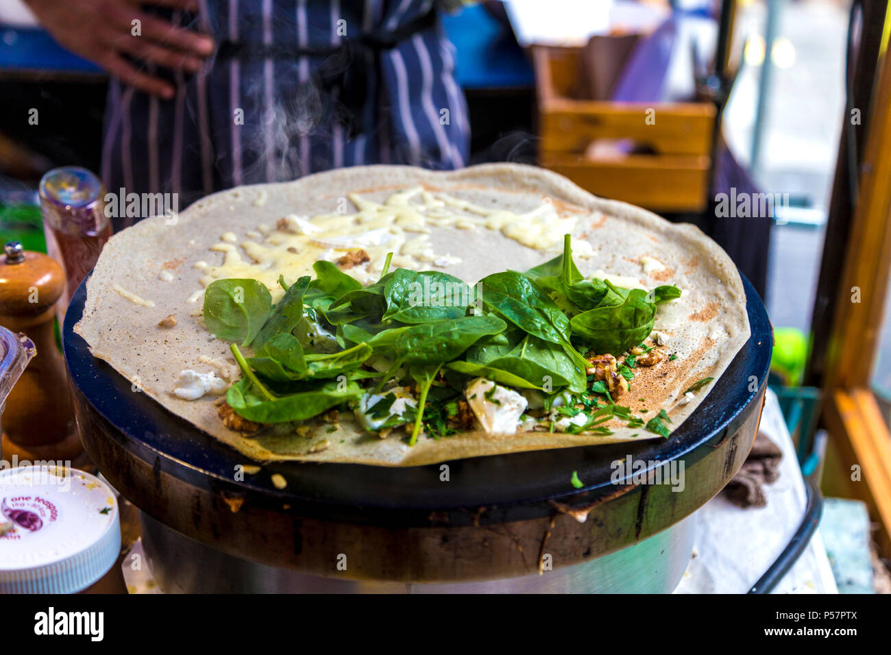 Preparation of a galette on a hotplate at a street food vendor stall (Greenwich Market, London, UK) Stock Photo