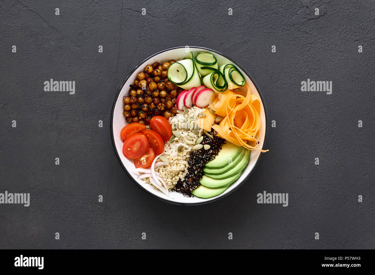 Vegetarian buddha bowl. Clean and balanced healthy food concept. Rice, spicy chickpeas, black and white quinoa, avocado, carrot, zucchini, radish, tom Stock Photo
