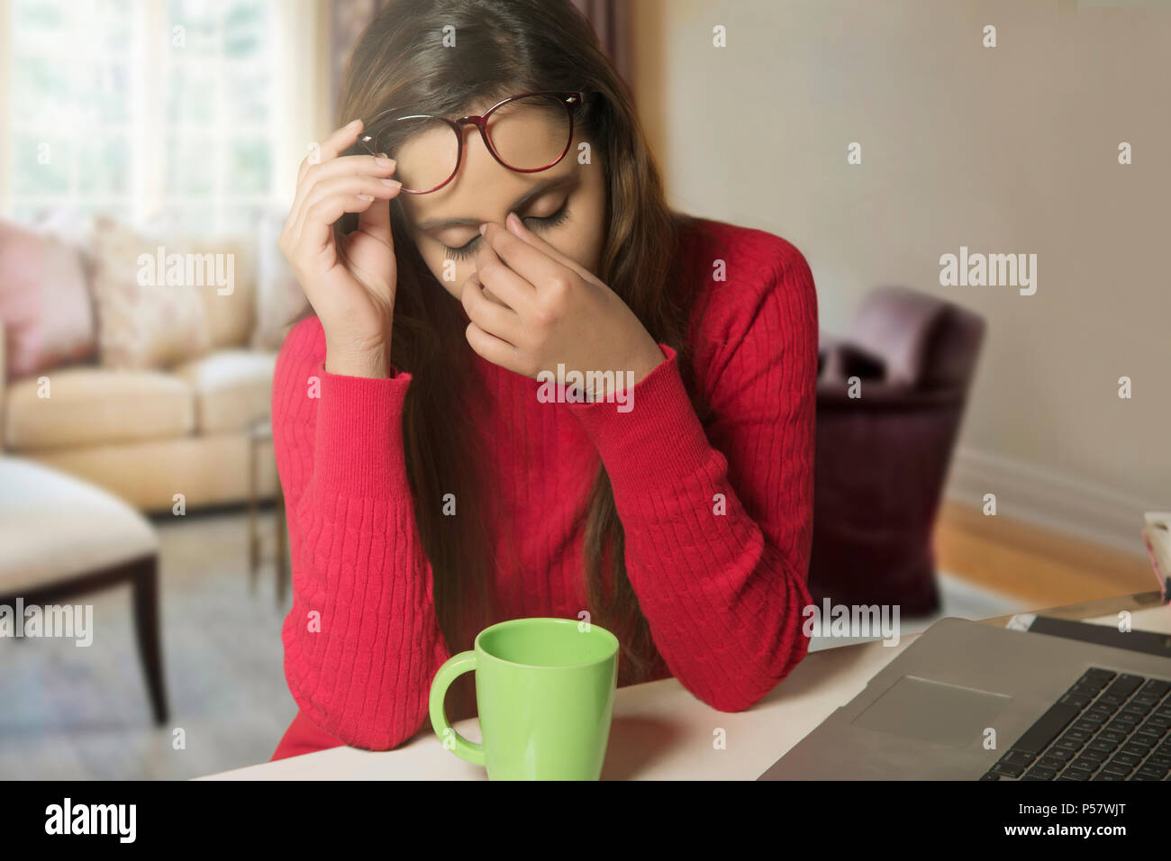 Stressed businesswoman at laptop with head in hands Stock Photo