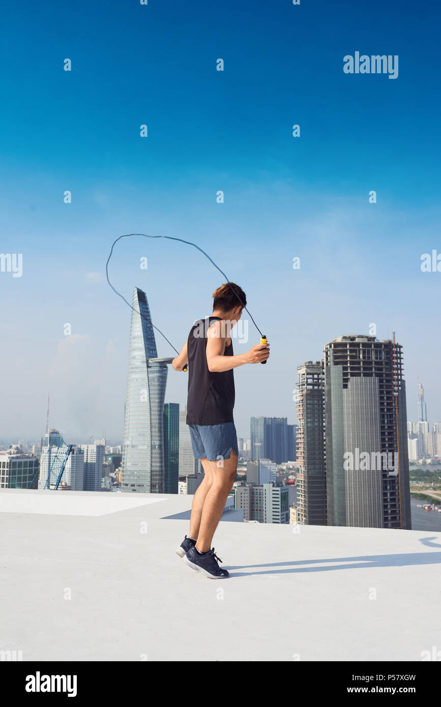 fitness, sport, people, exercising and lifestyle concept - man skipping with jump rope outdoors Stock Photo