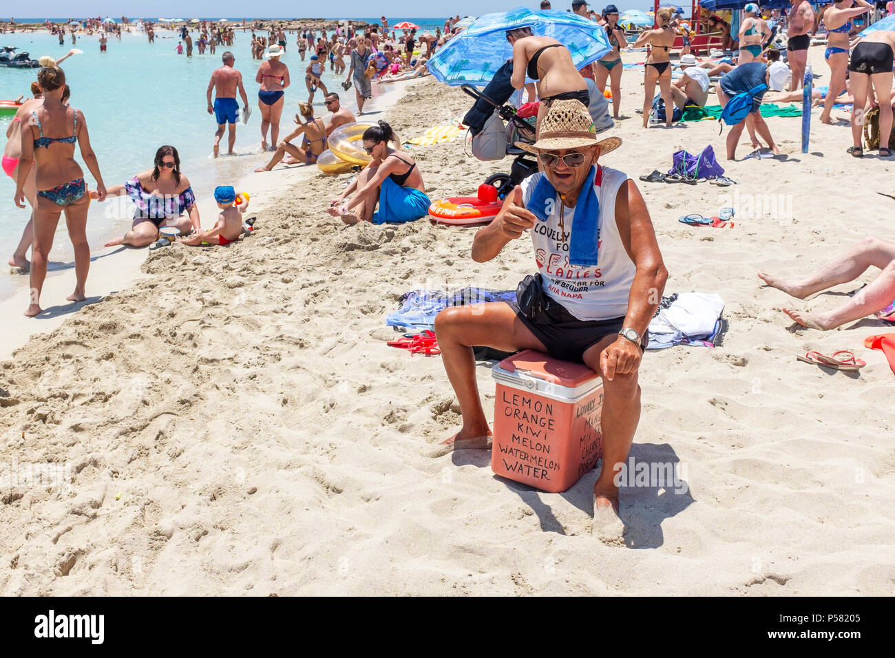 Local man selling fresh fruit and cool drinks from a fridge box, on Nissi beach, near Ayia Napa, Cyprus. Stock Photo