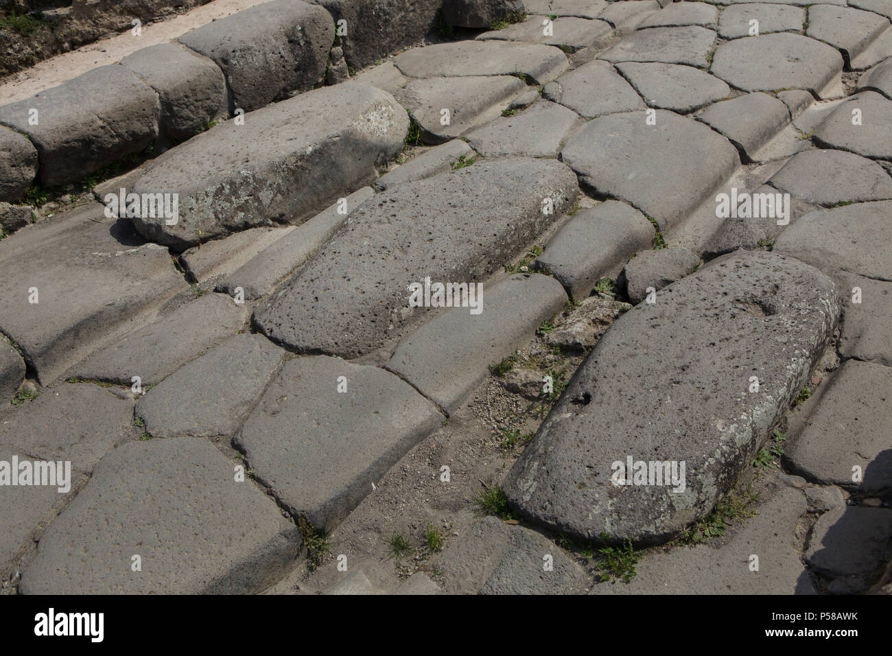 Traditional pedestrian crossing with gaps for chariots on the cobbled street in the archaeological site of Pompeii (Pompei) near Naples, Campania, Italy. Stock Photo